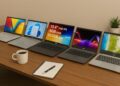 A lifestyle setup showing five different laptops placed diagonally on a wooden table with a coffee cup, notebook, and pen in the foreground, and a small plant in the background. The laptops include ASUS Vivobook, HP 15s, Lenovo IdeaPad, Acer Aspire, and ASUS Chromebook, all with screens turned on.