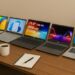 A lifestyle setup showing five different laptops placed diagonally on a wooden table with a coffee cup, notebook, and pen in the foreground, and a small plant in the background. The laptops include ASUS Vivobook, HP 15s, Lenovo IdeaPad, Acer Aspire, and ASUS Chromebook, all with screens turned on.