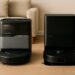 Eufy Omni C20 and Roborock Qrevo S5V robot vacuum stations side by side in a modern living room on wooden flooring.