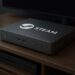 Steam Machine concept device on a wooden TV stand, minimalist design with multiple ports