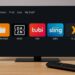 Amazon Fire TV home screen interface with installed apps and remote control on a desk.
