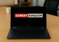 HP OmniBook X Flip 2‑in‑1 laptop on a wooden desk in a modern office, with the Expert Kingdom logo displayed on the screen